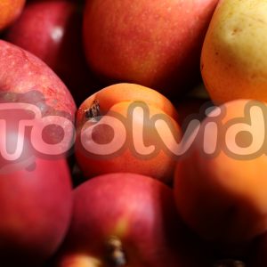 Un insieme di frutta gialla, rossa ed arancione che riempie tutta l'inquadratura. Ci sono mele rosse, albicocche e pesche. Immagine coperta da un watermark.